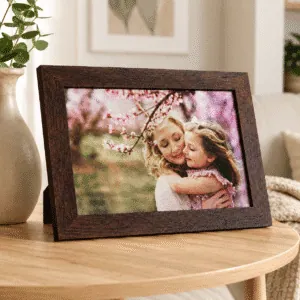 Cuadro portaretrato tamaño 20x30 marrón horizontal, apoyado en mesita de madera con foto de madre e hija, con impresión en tela de Canva montada en Sintra, sin vidrio